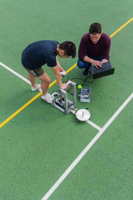 Φοιτητής και καθηγητής χρησιμοποιούν όργανα και υπολογιστή για μετρήσεις σε χώρο στίβου.